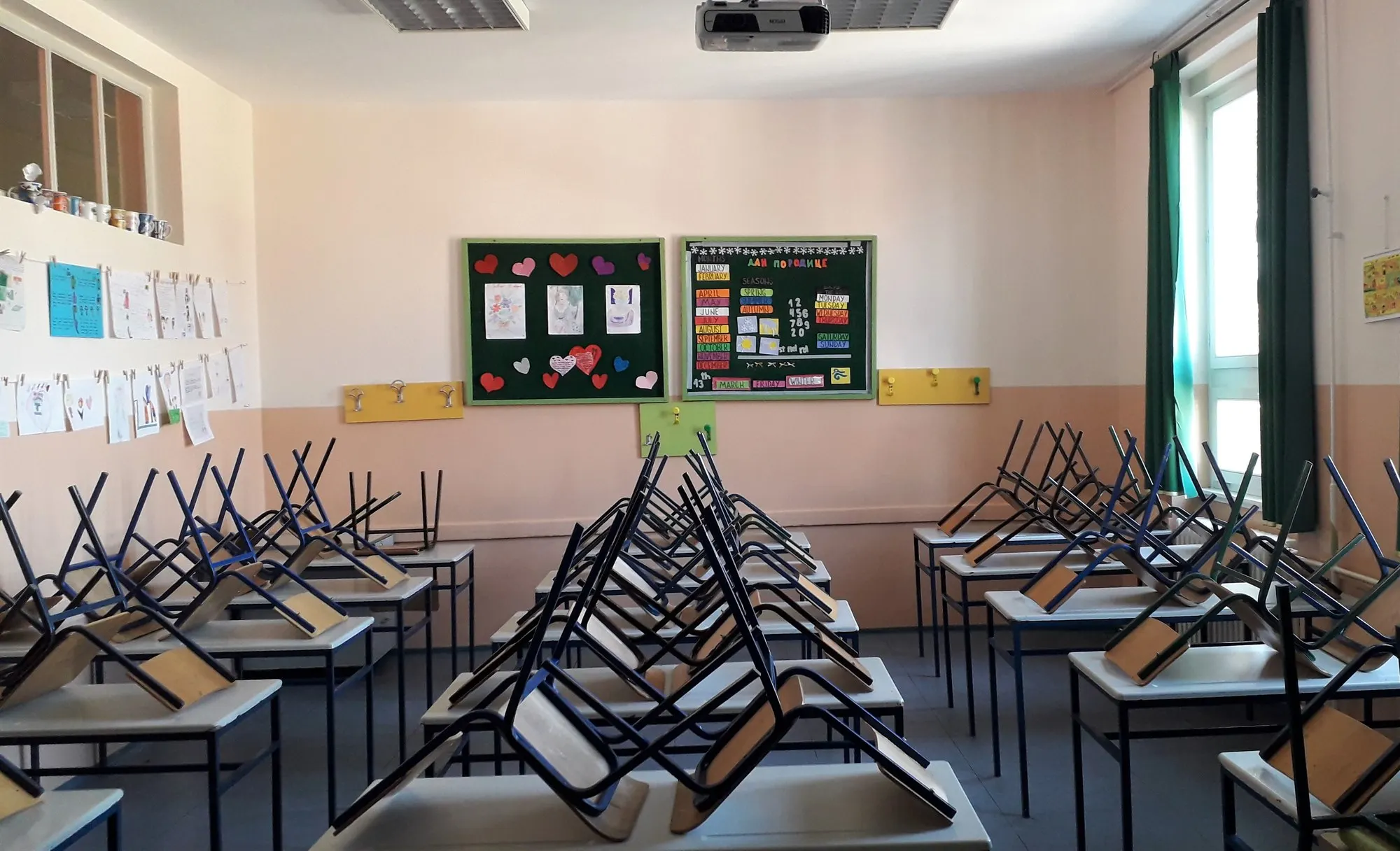 An empty classroom with chairs stacked on the desks.