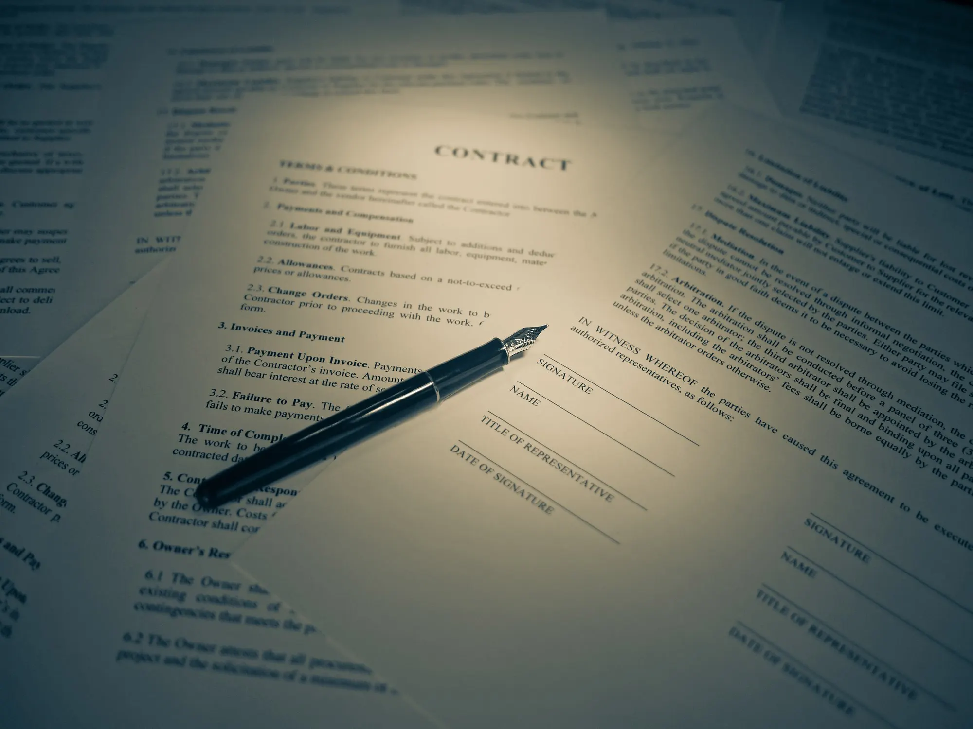 A signed legal contract with a fountain pen resting on the page.